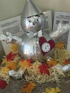 a silver statue with a heart on it sitting in hay next to fall leaves and books