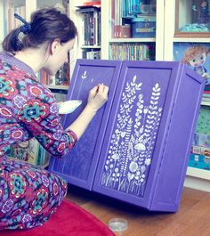 a woman is drawing on an easel in front of bookshelves