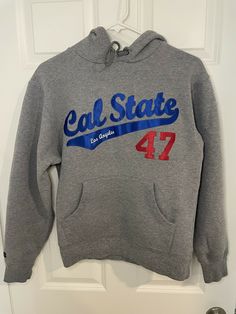 Cal State Los Angeles CSLA LA Sz XS Extra Small Gray Hoodie Embroidered Sweater. The logo is in the style of the LA Dodgers. Very cool piece. On a JanSport tag. PLEASE NOTE: The embroidery does have a FLAW, it is missing a piece of string about 1 inch long under the Cal. So the patch is not flush to the sweater. See photos for details. Please also note that this is a VERY SMALL sweater, please check the measurements before purchasing. Measurements are approximate while laying flat. Armpit to arm Cal State, Gray Hoodie, Small Sweater, Embroidered Sweater, Grey Hoodie, 1 Inch, Angeles, Embroidery, ? Logo