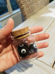 a hand holding a glass jar with fake eyelashes in it