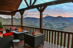 an outdoor deck with chairs and tables overlooking mountains