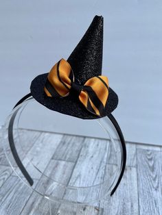 This little witch hat fascinator is perfect for Halloween or any day of the year! Hat is attached to a plastic headband covered with black silky material. Headband is soft and flexible, which makes for a comfortable fit. It is a standard size headband, which will fit both adults and older children. Witch hat is made of glitter foam and is attached to the headband, but is able to slide on the headband so you can wear the hat on the top of your head or on either side. Hat is adorned with a gold an Halloween Cat Ears Costume Accessories, Themed Party Headband Costume Hats, Spooky Black Costume Hats And Headpieces For Halloween, Adjustable Black Witchy Costume Accessories, Black Adjustable Witchy Costume Accessories, Adjustable Cat Ears Costume Accessories For Halloween, Gold Costume Hats And Headpieces For Halloween, Adjustable Cat Ears For Halloween, Gold Costume Accessories For Halloween Cosplay