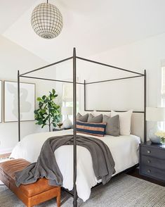 a bedroom with a four poster bed, white walls and gray carpeting on the floor