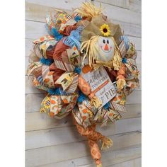 a scarecrow wreath hanging on the side of a wooden wall