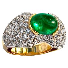 This elegant 18k yellow gold Late-20th century ladies dome ring is set with one rich green natural Colombian emerald double cabochon weighing approximately 3.15ct. Color saturation in this gem is very intense and uniform. GIA report number 2239214304 which states that the emerald is F2*enhanced will be delivered with the ring.Flanking this very well saturated and transparent gem are a total of approximately 86 round brilliant cut diamonds having a total approximate weight of 1.75ct and an overall quality of H color and VS1 clarity. The 18k yellow gold mounting is expertly crafted with sizing spring and comfort grill and, the design area measures 7/8 inches by 1/2 inch, making this beautiful vintage ring impossible to overlook. The emerald rises a full 3/8 inches above the finger. Size is 6 Luxury Green Dome Ring With Polished Finish, Beautiful Rings Vintage, Dome Ring, Colombian Emeralds, Rich Green, Domed Ring, Late 20th Century, Vintage Ring, Round Brilliant Cut Diamond