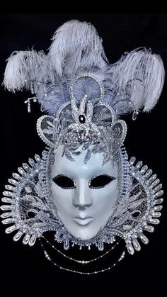 "Tudor Belle" is decked in a silvery cream, embroidered damask which has been fully hand-glitzed with Rhinestones and Swarovski elements and decorated with seed pearls, glass beads and ostrich feathers. Her ruff is made from antique silver lace with strings of glass beads and seed pearls suspended below it. Multi-coloured crystallised pendants hang from silver 'antlers' above and around her triple tiara.  As with all my work, this mask is a one-off and is signed and catalogued for preservation o Venetian Masks Art, Elegant Masquerade Mask, Masquerade Decorations, Madi Gras, Lion Couple, Midnight Masquerade, Venetian Masquerade Masks, Venetian Masquerade, Venetian Masks