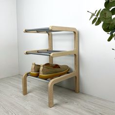 there is a shoe rack with two pairs of shoes on it next to a potted plant