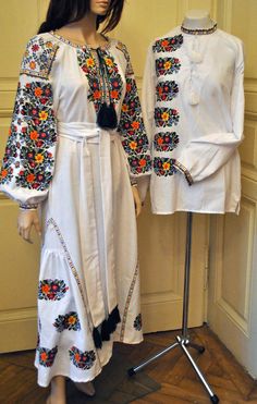 a woman standing next to a mannequin wearing a white dress with colorful flowers on it