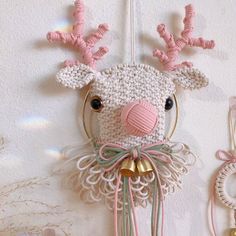 a crocheted deer head hanging on the wall next to two bells and rings