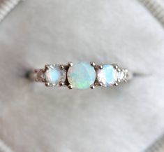 Australian opal + moonstone + diamond ring. Same design can be also made with other gemstones per request. Item details: 5mm faceted australian opal 4mm rainbow moonstones 2.3mm diamonds F - G color, VS clarity Metal: 14k/18k/platinum Sizes available: 3.5-8 Larger and smaller sizes are available. Priced upon request. ITEM WILL BE SHIPPED WITH EXPRESS SHIPPING - DHL EXPRESS SHIPPING ★ ★ ★ ★ ★ ★ ★ ★ ★ Enter my shop here: http://www.etsy.com/shop/MinimalVS ★ ★ ★ ★ ★ ★ ★ ★ ★ Opal Birthstone Ring In White Gold, White Opal Birthstone Promise Ring, White Opal Birthstone Ring With Gemstone, Fine Jewelry White Opal Birthstone Ring, White Opal Ring With Round Cut, White Round Cut Opal Ring, Opal Jewelry With Rose Cut Diamonds, Oval Ethiopian Opal Moonstone Ring, Round Opal Jewelry With Rose Cut Diamonds