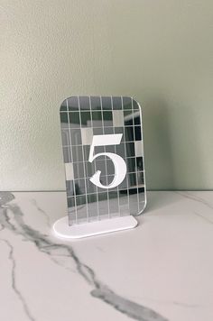 a marble table with a silver and black tile number five on the front, standing upright