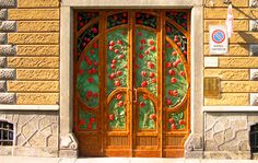 an ornate wooden door on the side of a stone building with flowers painted on it