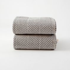 two towels folded on top of each other in grey and white herringbones pattern