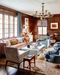 a living room filled with furniture and wooden paneled walls, along with a chandelier hanging from the ceiling