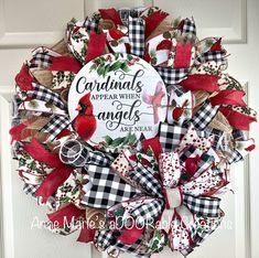 a red and black christmas wreath with cardinals, plaid bows and an angel is on the front door