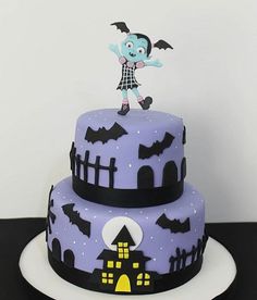 a three tiered cake decorated with purple icing and black fondant decorations, featuring a cartoon character on top