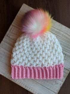 a crocheted hat with a pink and white pom - pom on top