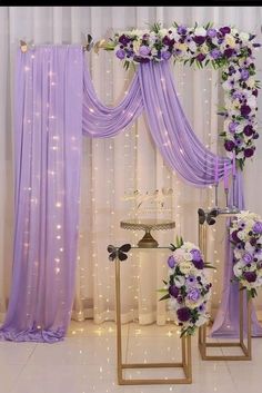 purple and white flowers are on display in front of the wedding ceremony arch with lights