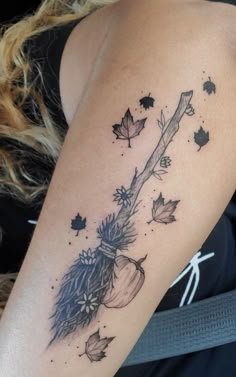 a woman's arm with an arrow and leaves tattoo on the back of her shoulder