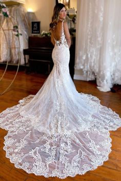 a woman in a wedding dress standing on a wooden floor with her back to the camera