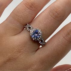 a woman's hand with a blue and white diamond ring on top of it