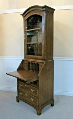 an old wooden desk with a glass door on it's top shelf and bottom drawer