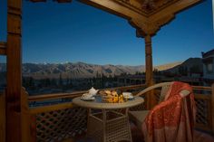 a table and chairs on a balcony with mountains in the background