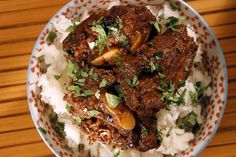 a bowl filled with rice and meat on top of a wooden table