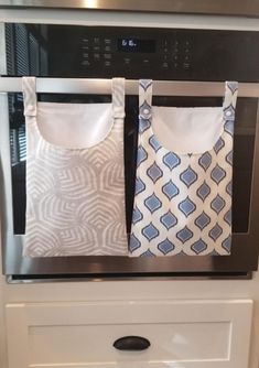 two aprons are hanging on the oven's front door, one is blue and white