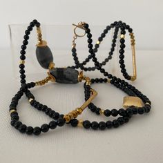 Wear this asymmetrical necklace long or double wrap it for a short necklace. Onyx gemstones are mixed with gold bars and gold beads. This necklaces is approximately 40 inches long. Elegant Double Strand Long Necklace With Natural Stones, Elegant Gold Onyx Beaded Necklaces, Gold Onyx Gemstone Necklace, Gold Multi-strand Necklace With Black Beads, Gold Necklaces With Natural Stones For Layering, Gold Onyx Necklaces With Natural Stones, Modern Gold Necklaces With Natural Stones, Modern Gold Necklace With Natural Stones, Gold Onyx Beaded Necklaces With Black Beads