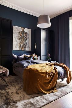 a bedroom with dark blue walls and an art work on the wall