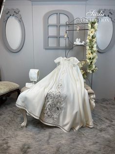 a white dress is on display in a room with furniture and flowers around it,