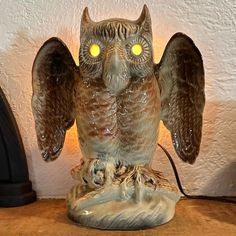 an owl figurine sitting on top of a wooden table next to a lamp