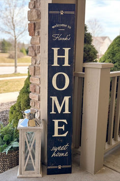 a welcome home sign sitting next to a brick wall with a lantern on the porch