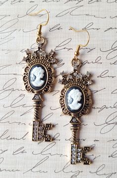 Add some elegance and a hint of romance to your accessory collection. The keys with cameo silhouette are encrusted with diamond-like crystals, swirl designs, and a white on black silhouette cameo lady. The earrings are created of goldtone plated precious metals and hypoallergenic ear hooks. These earrings will surely be the key to any onlooker's heart. Length: 3 inches Width: .75 inches  Purchases will be shipped within 3-5 business days, unless requested otherwise. Packages are shipped via USPS Elegant Cameo Earrings As Gift, Elegant Cameo Earrings For Gift, Cameo Drop Earrings Jewelry Gift, Cameo Drop Earrings As Gift, Gift Cameo Drop Earrings Jewelry, Elegant Cameo Metal Jewelry, Elegant Cameo Drop Earrings, Elegant Metal Cameo Jewelry, Cameo Drop Earrings For Gifts