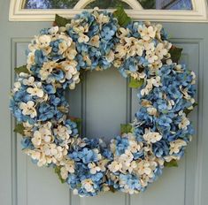 a wreath with blue and white flowers hanging on a door