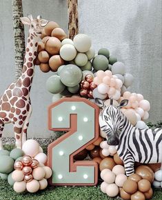 an animal themed birthday cake with balloons in the shape of numbers and giraffes