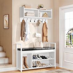 a white shoe rack with shoes and coats hanging on the wall next to a door