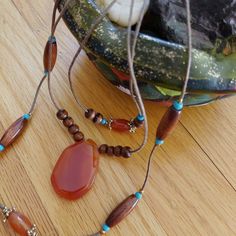 Earth Elements. Smoldering Carnelian. The central stone is dark orange, deeply spiced almost. Multi-strand, three, includes blue turquoise beads. Lots of seasonal contrast with tinted wood. The mood is sultry, with fiery effects. Good layering statement. Threaded on a natural brown cord. 20" length. Lobster clasp. Gift boxed. VINTAGE Artisan Orange Beads, Gems, And Cabochons For Gifts, Adjustable Bohemian Carnelian Beaded Necklaces, Spiritual Brown Beads, Gems, And Cabochons With Natural Stones, Spiritual Brown Natural Stones Beads And Cabochons, Spiritual Brown Beads For Jewelry Making, Bohemian Brown Beads Gems And Cabochons For Gifts, Bohemian Brown Beads And Cabochons For Gifts, Bohemian Carnelian Beaded Necklace For Gift, Bohemian Carnelian Beaded Necklace As Gift