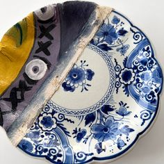 a blue and white plate with an eye on it's side, next to a piece of paper that has been cut in half