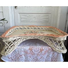 a wicker bench sitting on top of a table next to a white door with lace