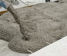 cement being poured onto the ground with a shovel and bucket in the backgroud