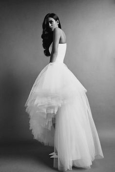 a woman in a white dress is standing on a gray background with her back to the camera