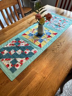 a wooden table topped with a potted plant and a quilted placemat on top of it