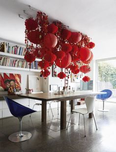 a dining room table with red lanterns hanging from it's ceiling and chairs around it