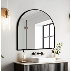 a bathroom with a mirror, sink and vase on the counter in front of it