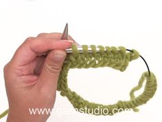 a hand holding a crochet hook and knitting the end of a piece of yarn