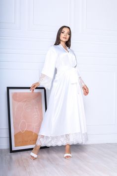 This white long robe is made of high-qualiry silk satin. It has long wide sleeves made of lace and wide belt. When you have one of the most important days in your life, everything should be perfect! You probably planned every minute of this day and now you are ready to make it real. The perfect day starts from the very morning which will be remembered every time you will look at your photos. The bride robe should be beautiful and comfortable at the same time so you could enjoy this day in full! White Robe With Lace Trim For Wedding Night, White Lace Trim Robe For Wedding Night, White Lace Trim Kimono For Wedding, Wedding White Kimono With Lace Trim, White Lace Trim Wedding Kimono, White Wedding Kimono With Lace Trim, Elegant Wedding Kimono With Lace Trim, Elegant Long Sleeve Robe For Bridal Shower, Long Wedding Robe With Lace Trim