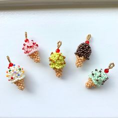 four ice cream cones are arranged on a white surface with bead charms attached to them