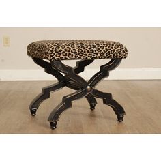 a leopard print foot stool sitting on top of a hard wood floor next to a wall